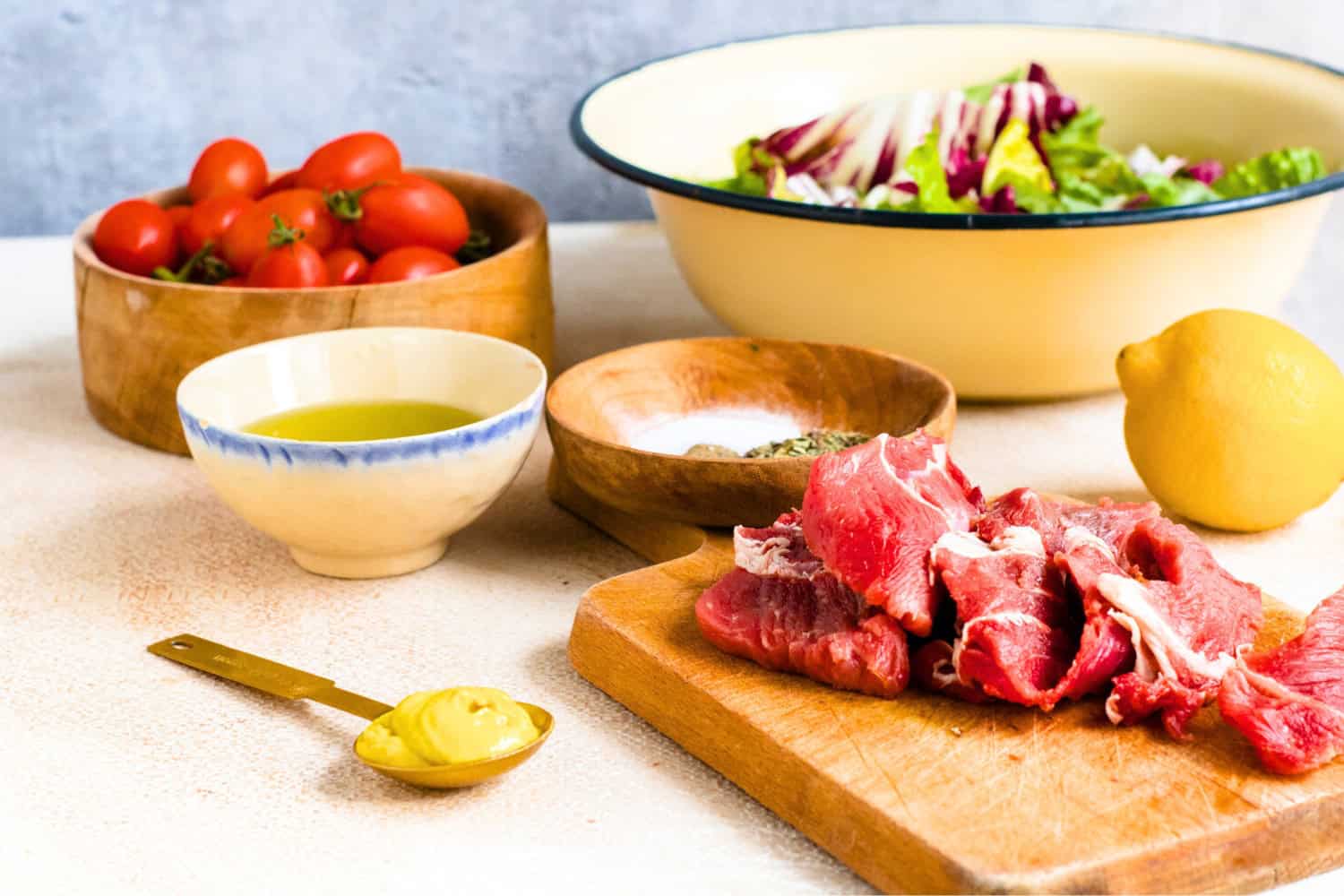 keto friendly foods such as beef, olive oil, mustard, baby tomatos, lemon, and salad