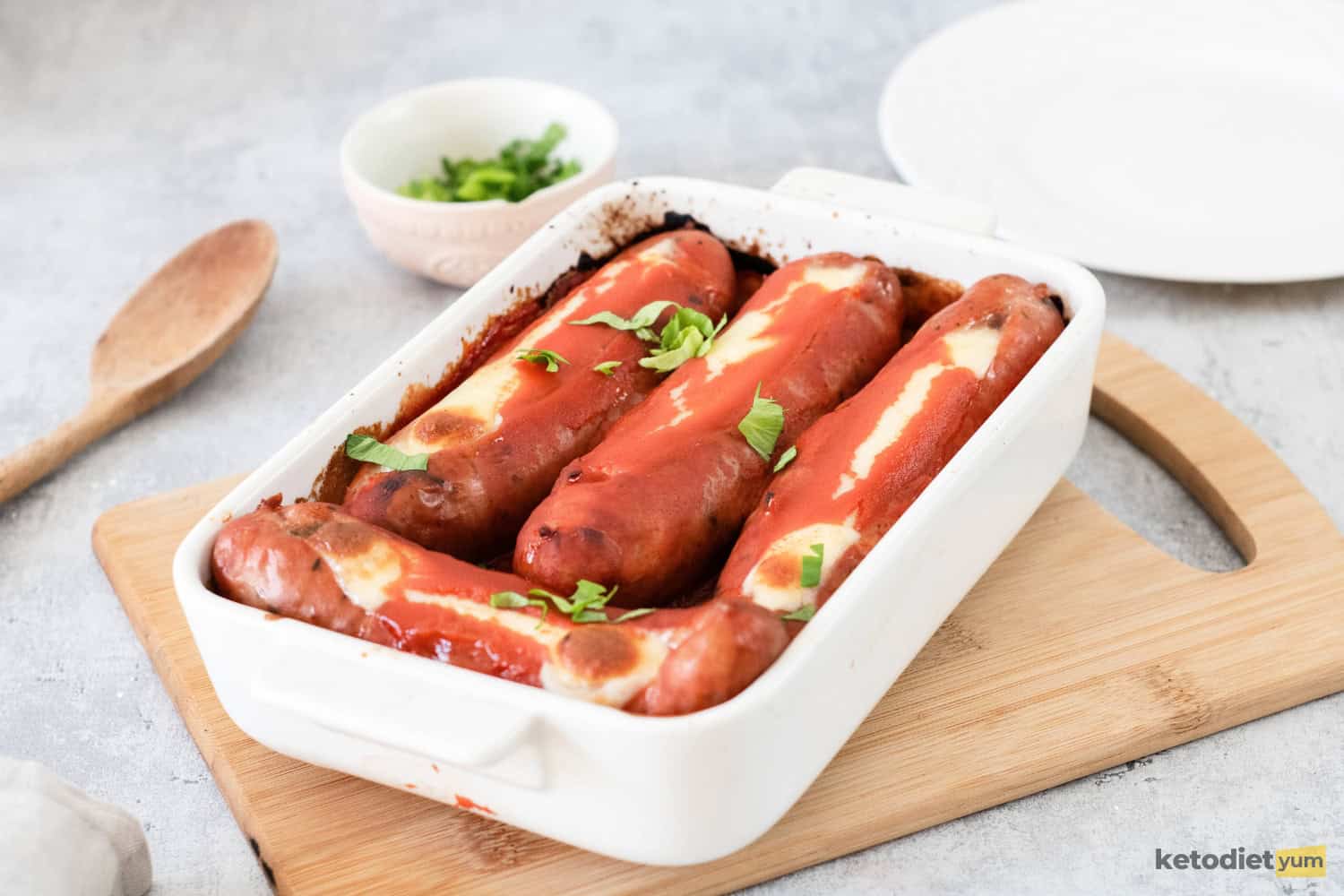 Baked stuffed sausages in a baking pan topped with marinara sauce and fresh parsley