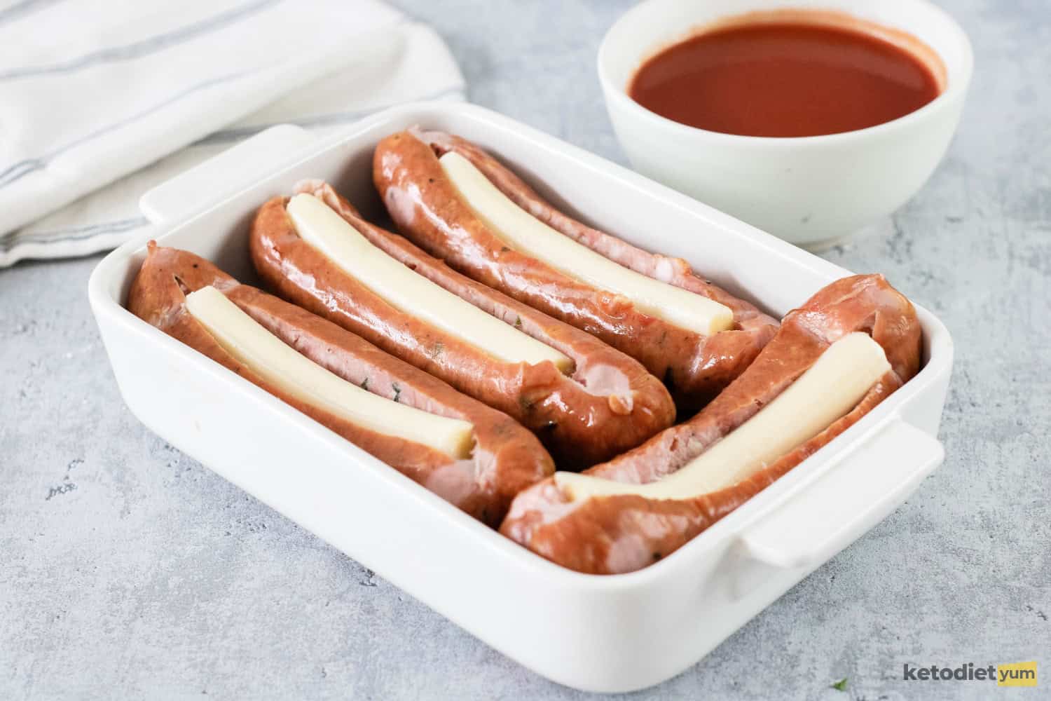 Italian sausages stuffed with mozzarella cheese sticks in a baking pan